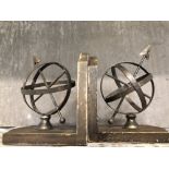A pair of metal book ends with globes as decoration.