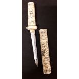 A Meiji period Japanese carved bone Tanto dagger decorated with figures.