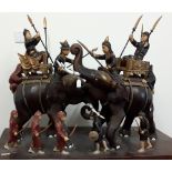 A large wooden diorama depicting a battle between two armed elephants and warriors.