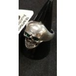 A silver ring in the form of a skull. Set with emerald eyes.