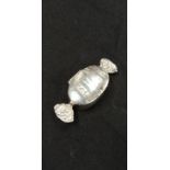 A silver pill pot in the form of a wrapped sweet.