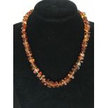 A string of polished amber beads of irregular form with silver clasp.