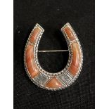 A silver horseshoe brooch set with coral.