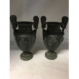 A pair of pewter urns on green marble bases.