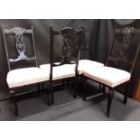 Four ebonised dining chairs, with white silk upholstered seats with amber coloured floral decoration