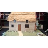 A hand built thatched doll's house with sliding front and battery powered electrics, with garden.