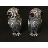 A pair of unusual silver condiments in the form of owls.