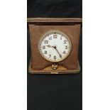 An eight-day travelling clock in tooled leather.