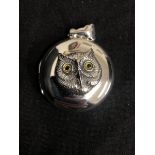 A silver pendant locket with embossed owl set with glass eyes.