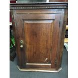 An antique oak corner cabinet, with brass handle and three fitted shelves.