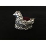 A silver pincushion in the form of a chicken.