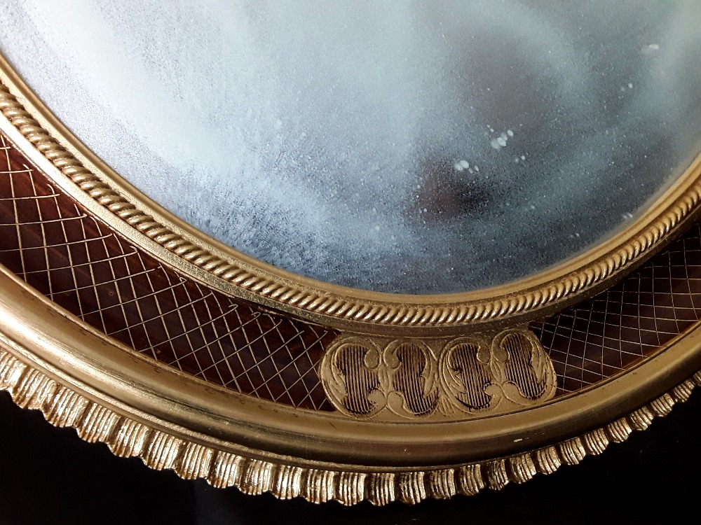 A large oval shaped mirror with bevelled edge to the glass enclosed in a gilded patterned frame. - Image 2 of 3