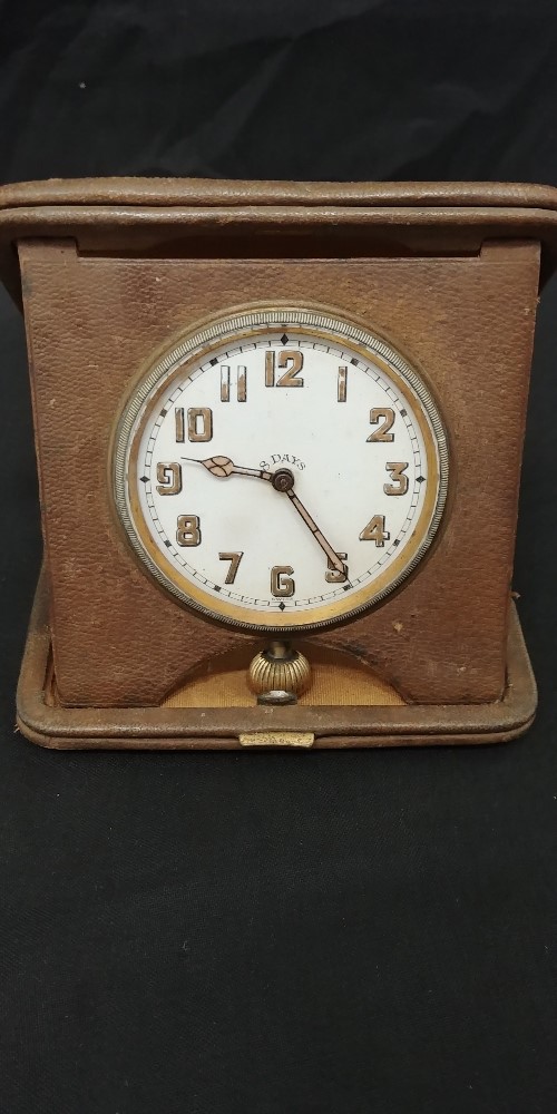 An eight-day travelling clock in tooled leather.