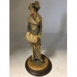 A resin figurine of a lady. Dated 1913. With two signatures. On wooden mount. Height 26cm
