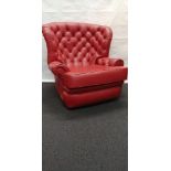A Chesterfield style button back chair in red leather upholstery.