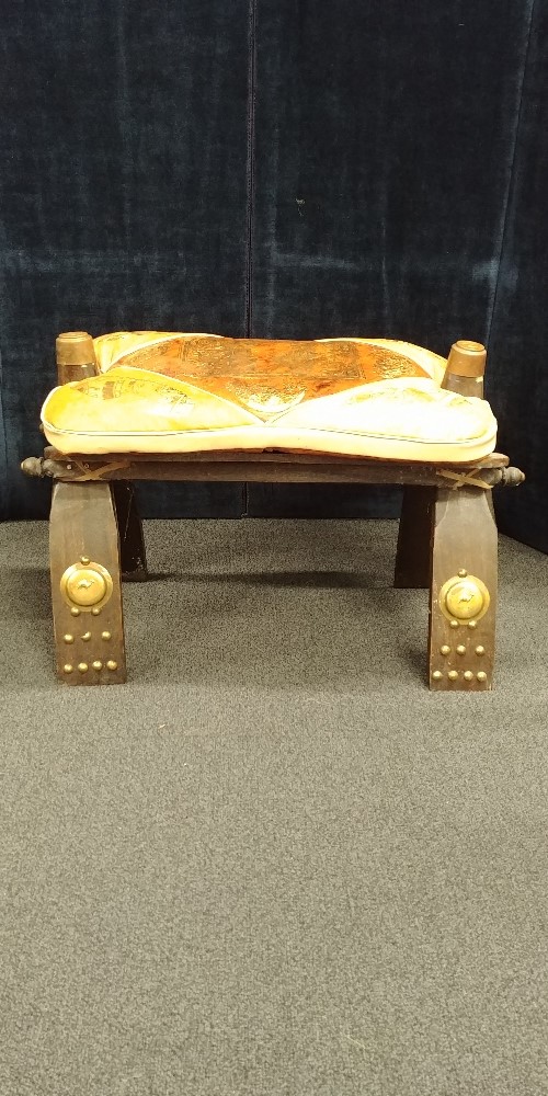 A camel stool with leather cushion decorated with Egyptian heads and art work.