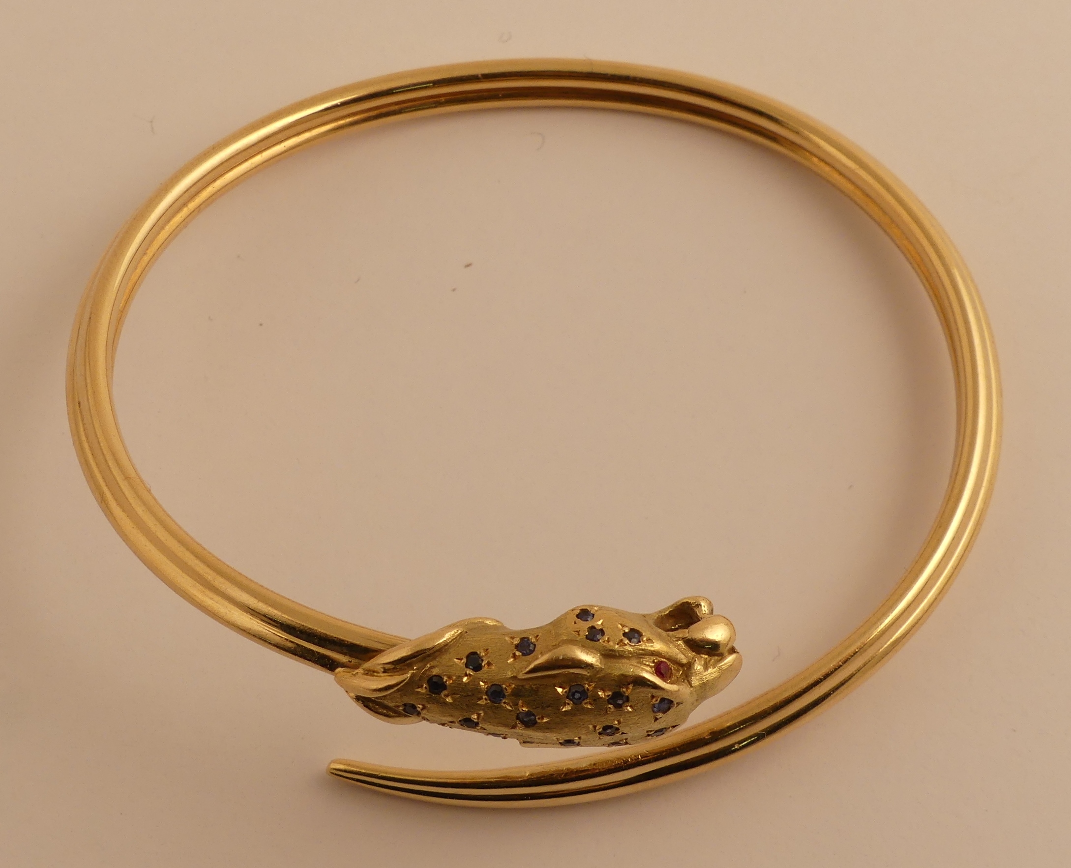Bracelet en or jaune figurant une tête de panthère serties de saphirs et rubis. PB. [...]