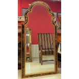 Miroir bisauté de forme mouvementée en bois laqué et doré. Haut : 133 cm. -