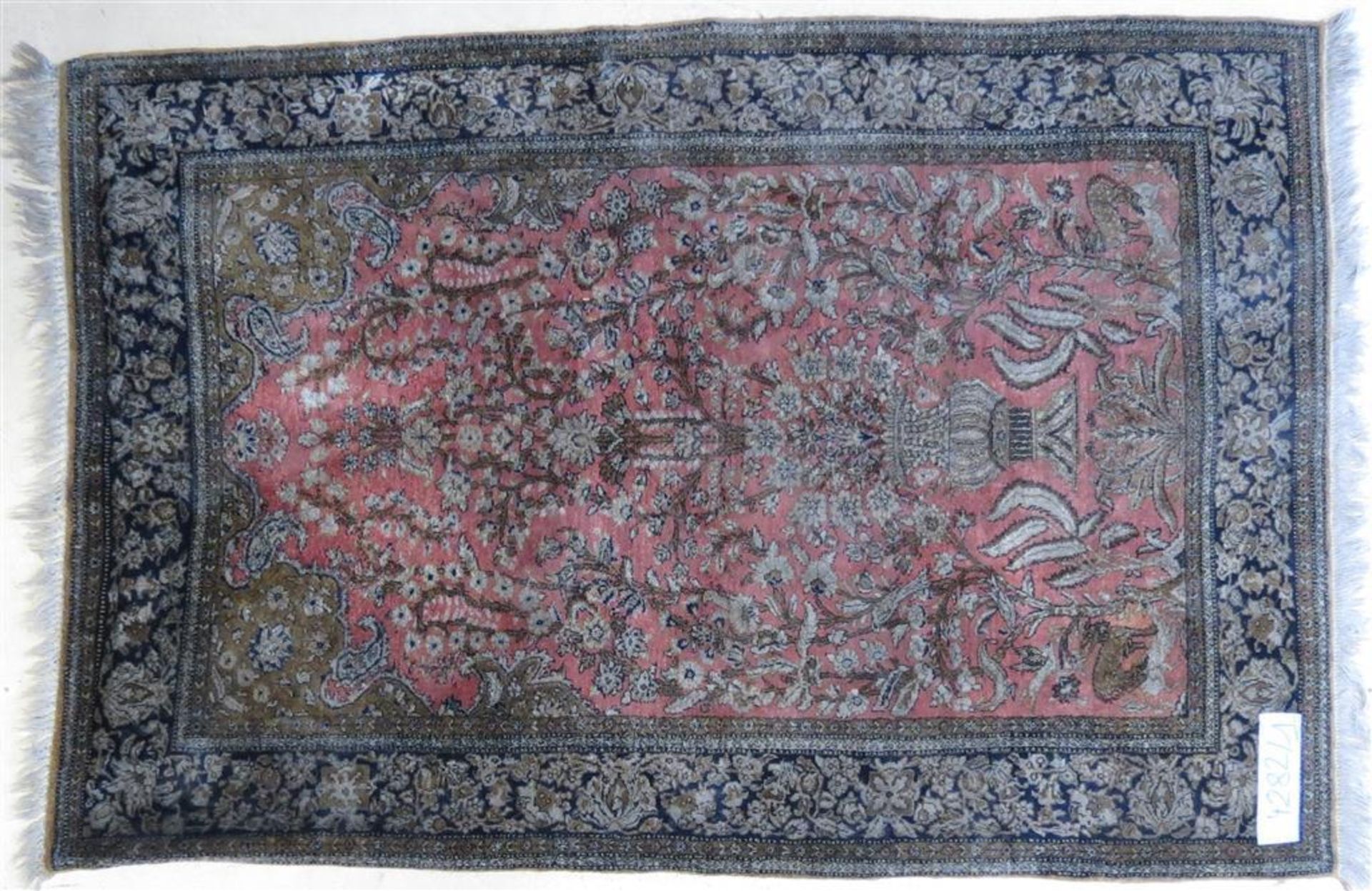 Tapis d'Iran en laine et soie à décor d'un vase fleuris sur fond rose. 155 x 106 cm. -