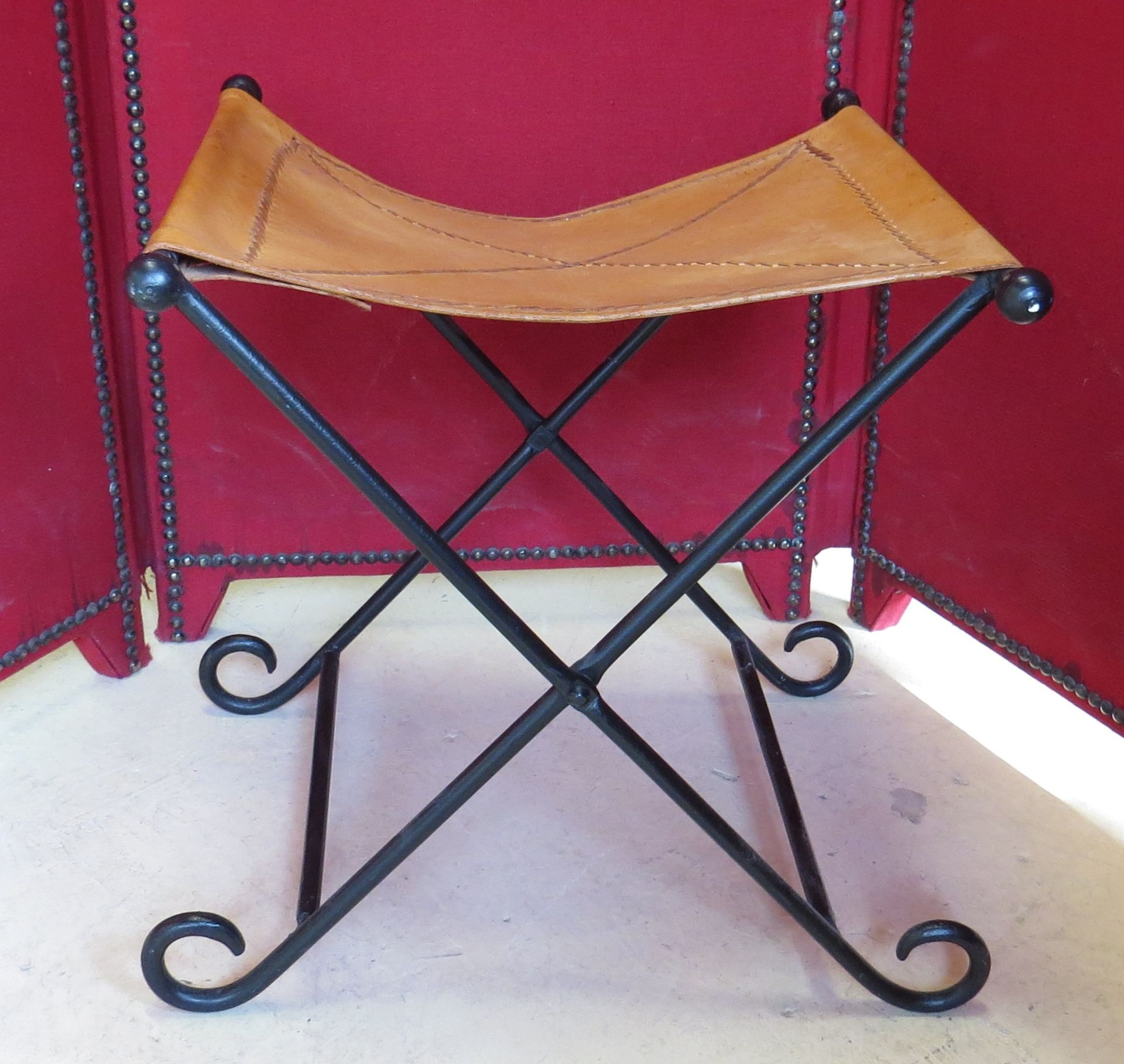 Tabouret curule en fer forgé. Assise cuir havane. -