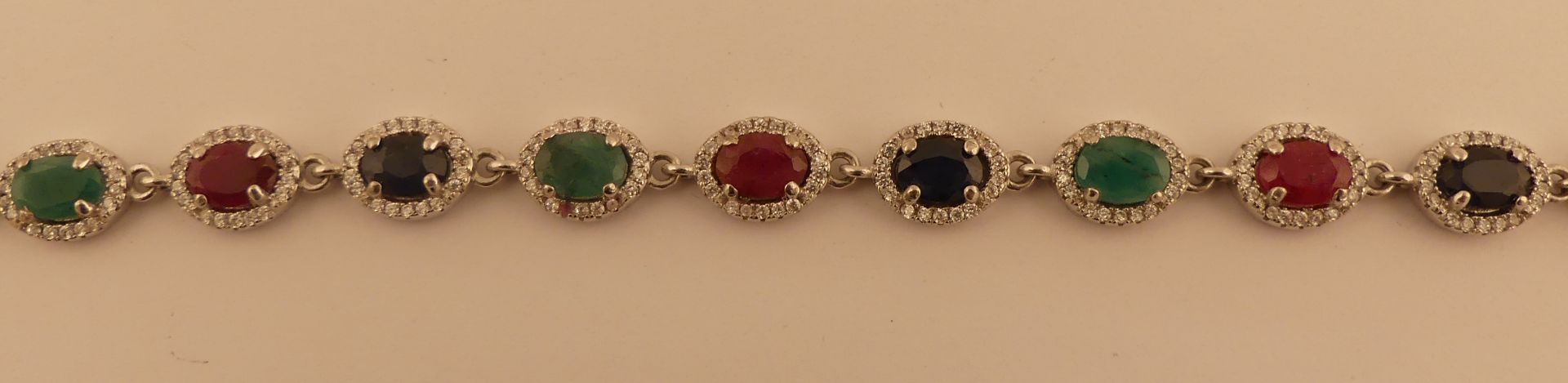 Bracelet en argent, agrémenté d'émeraudes, rubis, saphirs dans un entourage de [...]