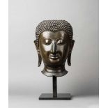 Großer Kopf eines Buddha. Heiterer Gesichtsausdruck. Betonte Brauenpartie. Lange Ohren. Frisur mit