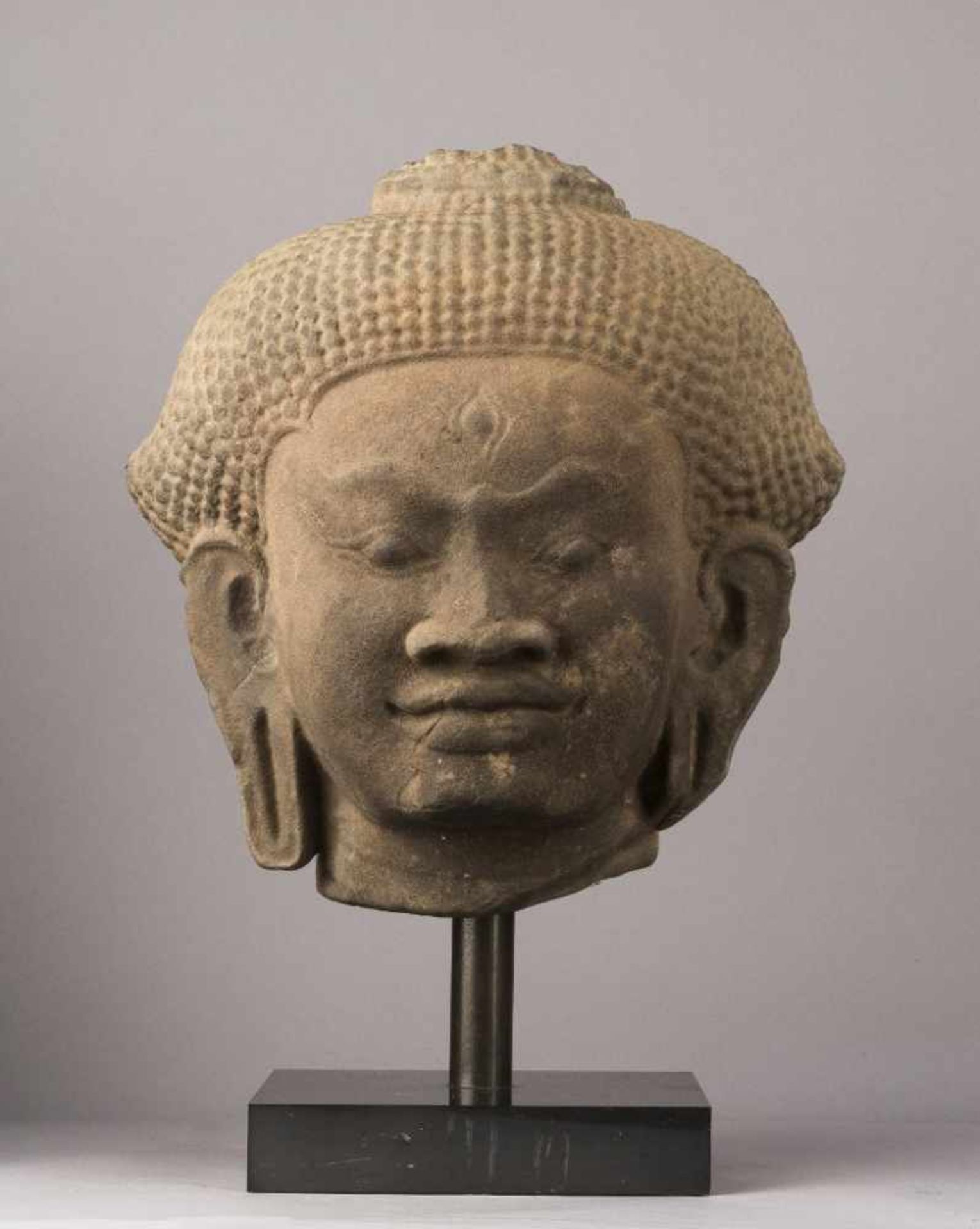 Mächtiges Haupt eines Buddha. Breite Nase und betonte Brauenpartie. Frisur mit kleinen Locken.