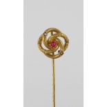 Goldene Krawattennadel in Form eines Knotens mit kleinen Orientperlen und rubinrotem Stein. GG. Ende