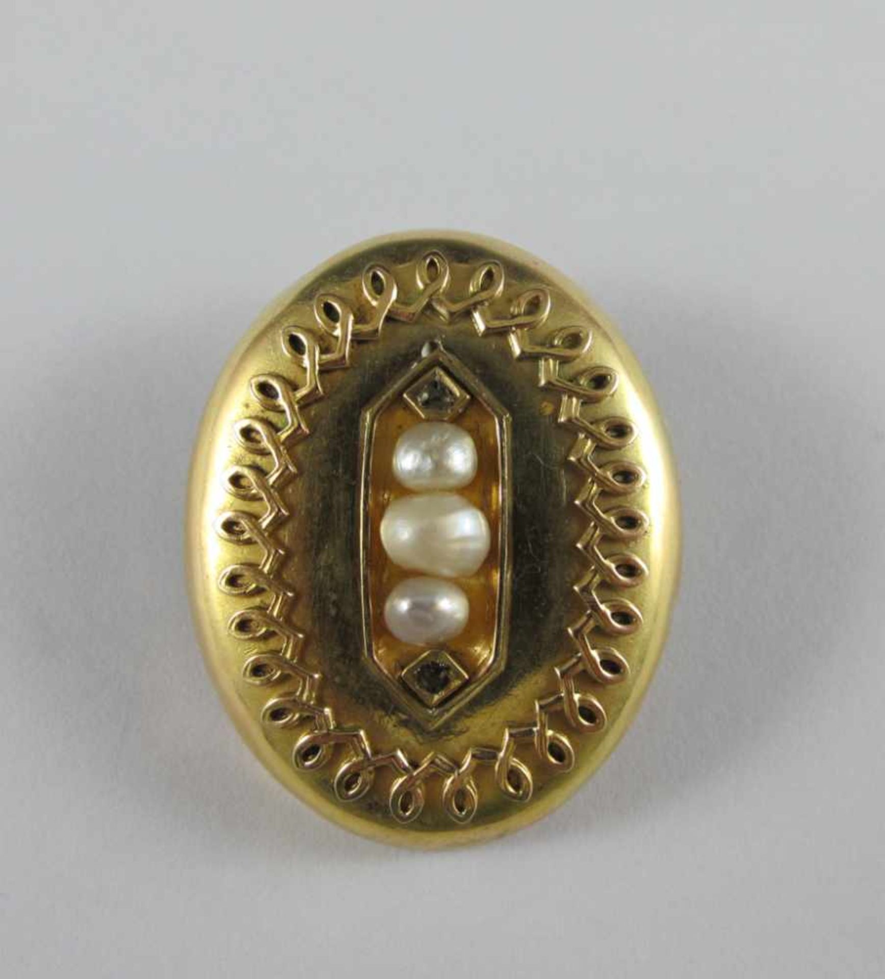 Ovale Brosche, auch als Anhänger zu tragen. 14 ct. GG mit Zierbelötung, Diamantrosen und Perlen.