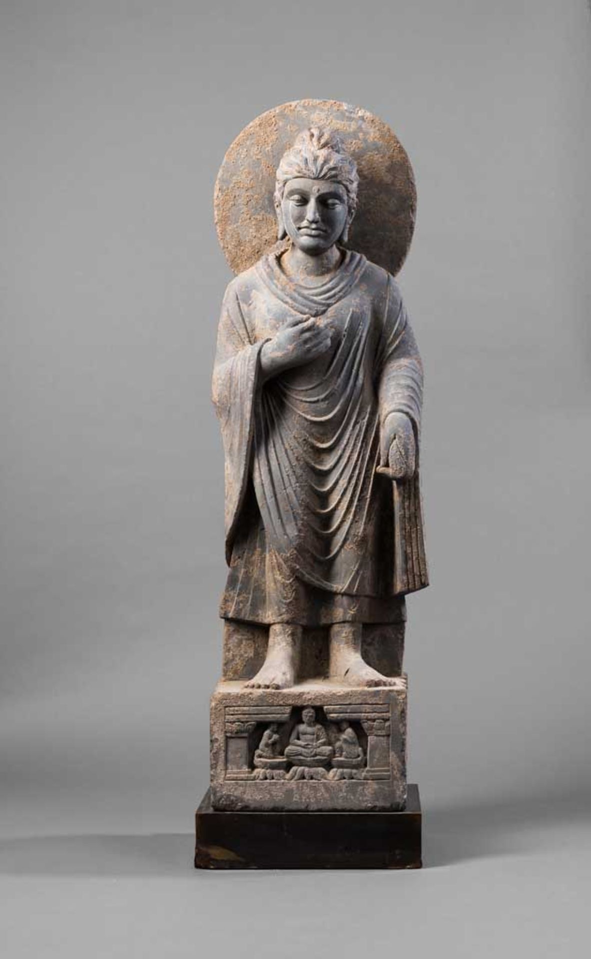 Stehender Buddha. Plinthensockel mit Adoranten. Den Kopf leicht zur Seite geneigt. Gesichtszüge