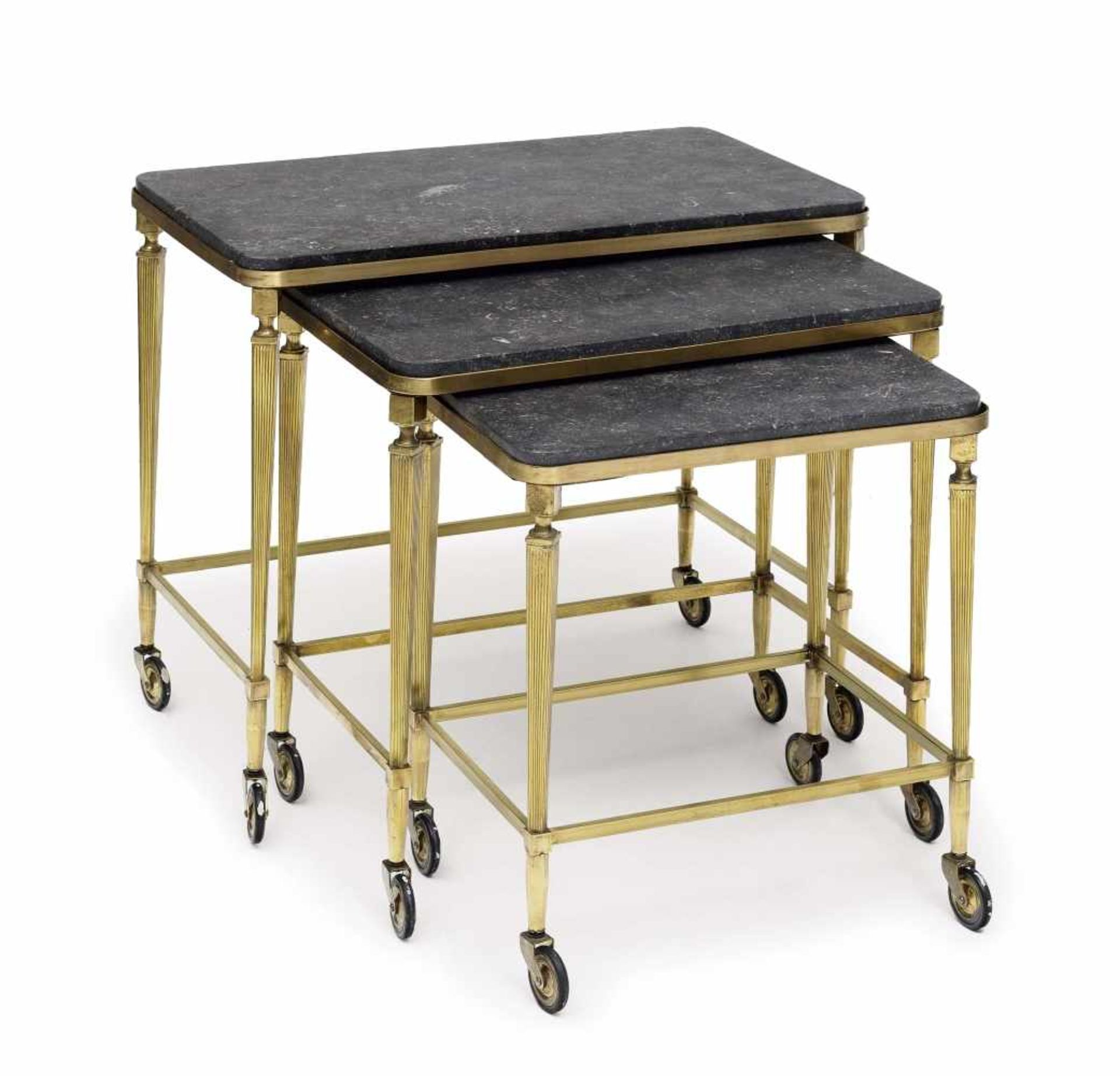 Three nesting tablesFrance or Italy, circa 1940/50 Brass, marble tops. Fluted legs on wheels. 53 x