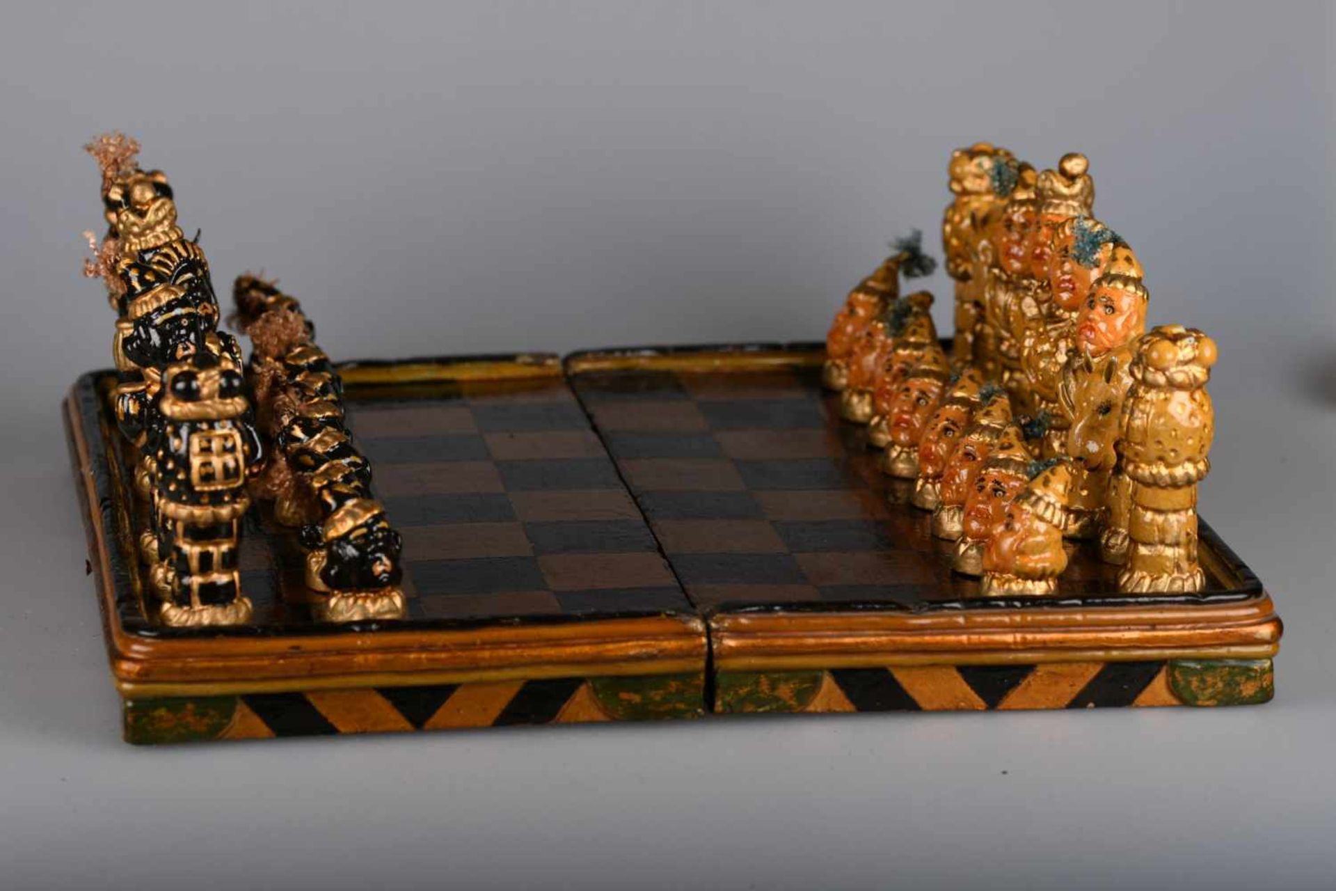 Kurioses SchachspielAufklappbare hölzerne Schatulle mit aufgemalten schwarzen und goldbronzenen