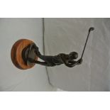 A copper golfing figure mounted on wooden base, me