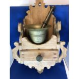 A brass apothecaries mortar and pestle on fitted carved wood wall bracket with single drawer, 46cm