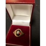 An oval facetted garnet in yellow gold ring with fancy rubover setting and filigree shoulders,