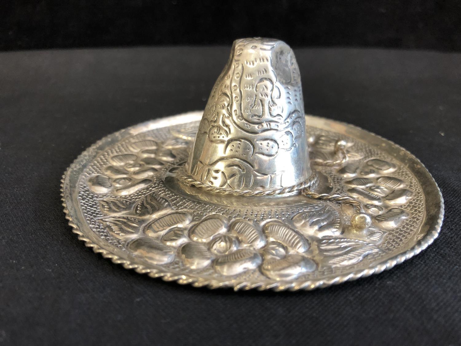 A Mexican sombrero hat pin tray, decorated with repousse work with further chasing of a garland of