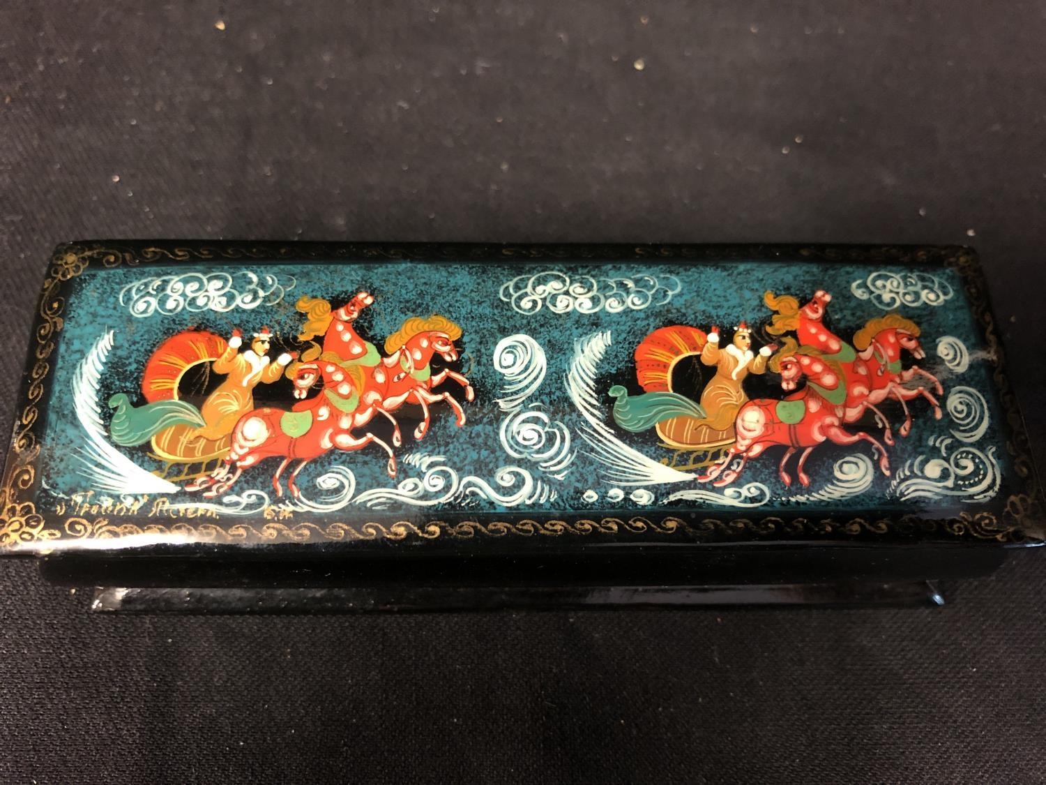 A Russian papier mache lacquer box, rectangular, decorated with two troikas, figures and horses,