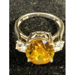 A citrine and cubic zircona ring, the oval cushion cut stone flanked by two circular CZ, set in