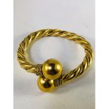 A gold torque bangle, twist design with rope detail wound through the centre and bound at each