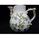 A Meissen porcelain jug, molded with a forget-me-not type plant, with ornate wishbone handle and
