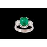 AN EMERALD AND DIAMOND THREE STONE RING, with IGI cert stating the emerald to be 4.16ct, flanked