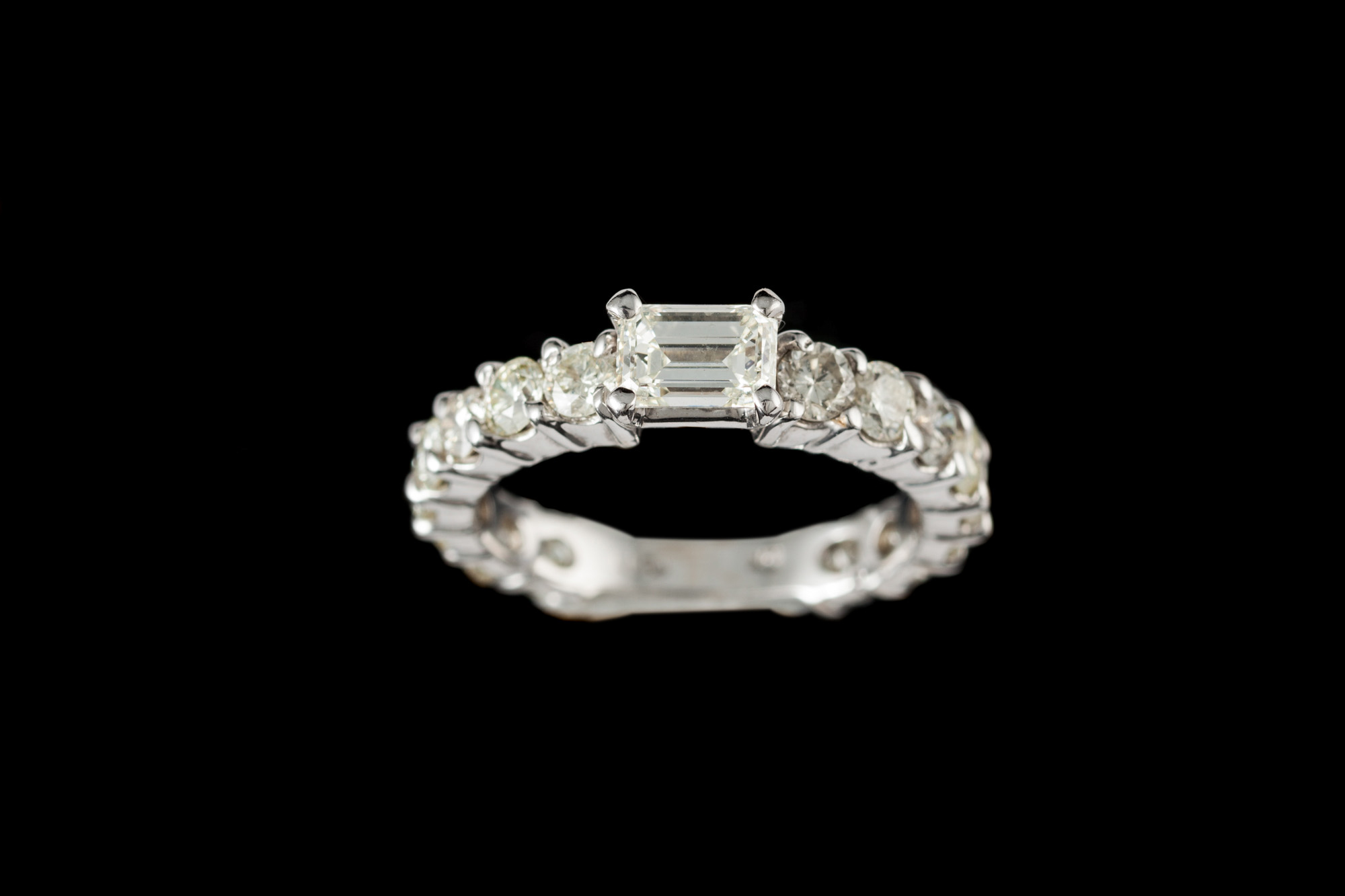 A DIAMOND RING, with centre emerald cut diamond of approx. 0.60ct I/J VS, on diamond band of approx.
