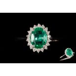 AN EMERALD AND DIAMOND OVAL CLUSTER RING, with emerald of approx. 1.05ct, diamonds of approx. 0.