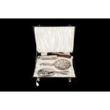 AN EDWARDIAN STYLE SILVER EMBOSSED FOUR PIECE DRESSING TABLE SET, comprising of a hairbrush,