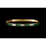 AN EMERALD AND DIAMOND HINGED BANGLE, of cushion shape profile, with emeralds of approx 3.