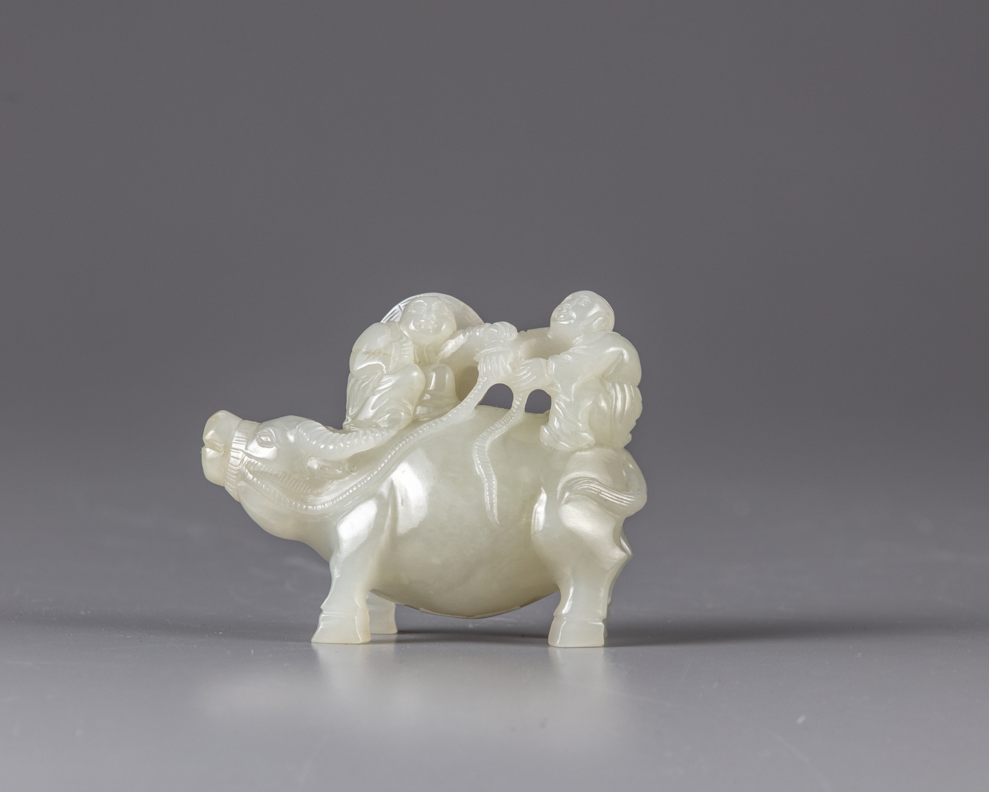 A pale jade carving of two boys on an ox