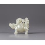 A pale jade carving of two boys on an ox