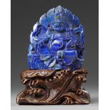 A Chinese lapis lazuli figure of Jambhala on a wooden stand