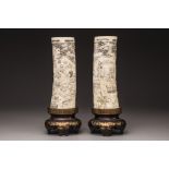 A pair of Japanese carved tusks on a wooden base