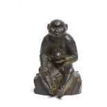 A large Japanese bronze figure of a monkey sitting on a rock with a peach in its hand